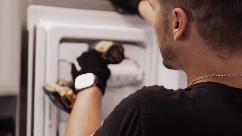 Appliance repair technician installing or repairing freezer ice maker unit