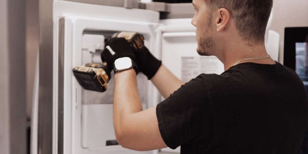 Close-up of technician fixing refrigerator ice maker inside freezer compartment